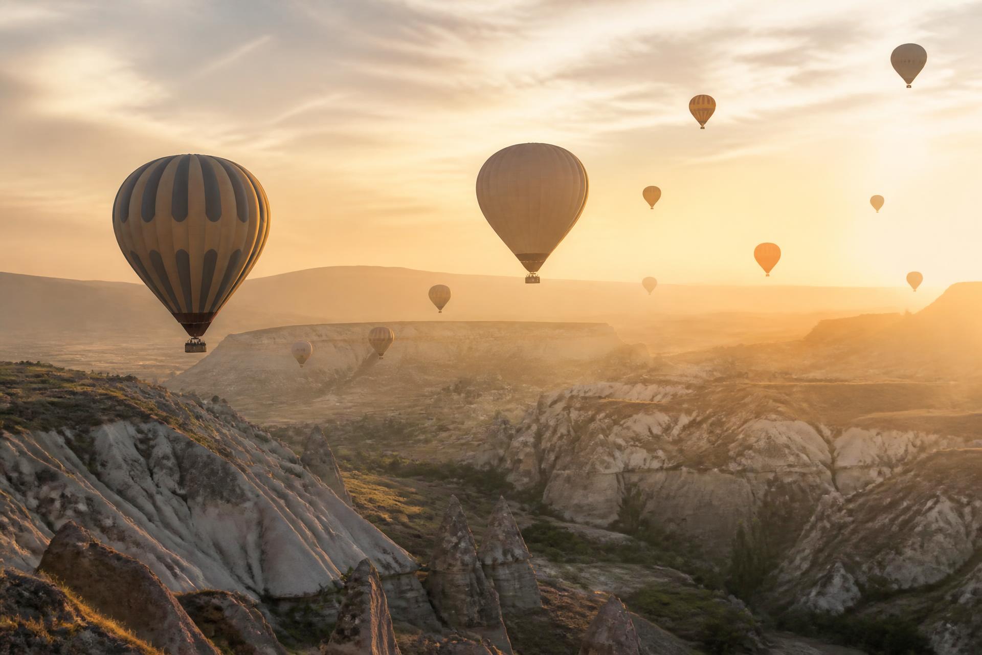 Hot air balloons rising over Cappadocia at sunrise
