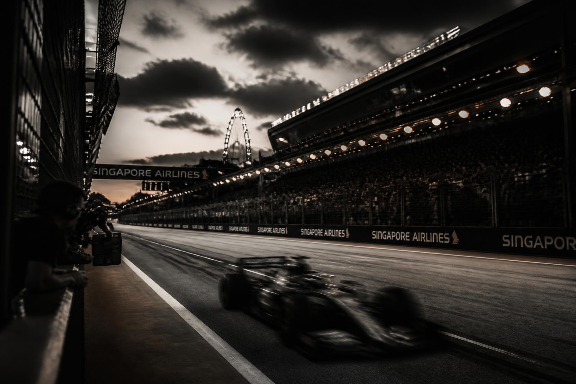 Formula 1 car on track at dusk under grandstand lights
